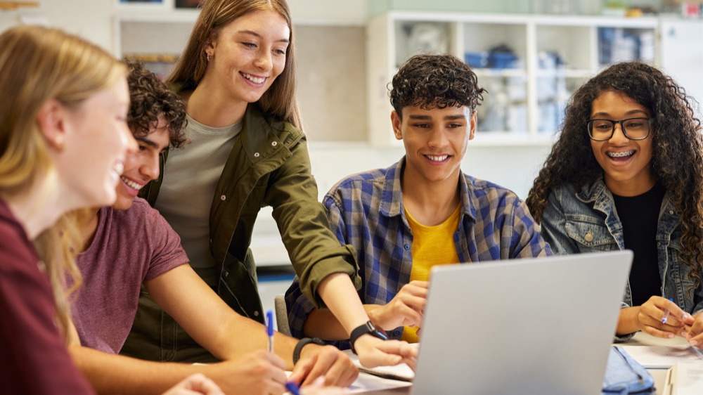 Students working together around a laptop in class